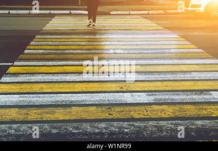 Una persona attraversa la strada in corrispondenza di un passaggio pedonale, la vettura passa un pedone passando attraverso una Zebra crossing. Foto Stock