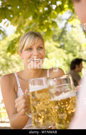 Coppia giovane in un giardino della birra bicchieri tintinnanti, il lago Starnberger, Baviera, Germania Foto Stock