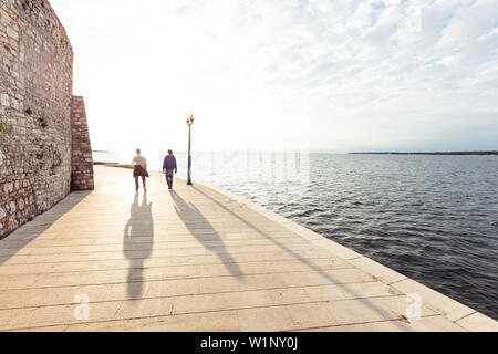 Due uomini a piedi lungo il lungomare di Parenzo in Istria, Croazia Foto Stock