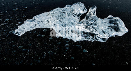 Joekulsarlon, Growler sulla spiaggia al sorgere del sole sulle pietre nere, Glacierlagoon, ghiacciaio Vatnajoekull, inverno, Islanda Foto Stock