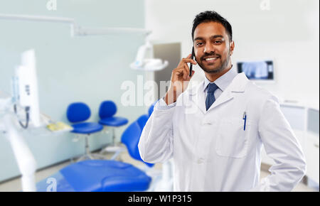Dentista chiamando sullo smartphone in clinica dentale Foto Stock