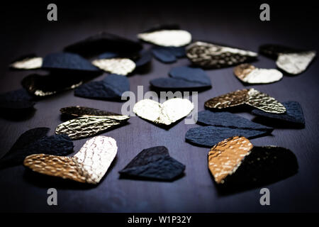 Gruppo di nero e lamina dorata cuori sul tavolo di legno Foto Stock