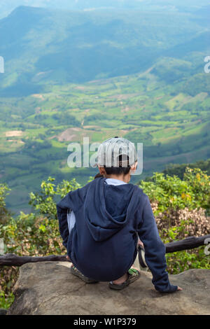 Ragazzi asiatici sedersi sulla roccia di vedere le montagne e il cielo di Phu Rua Parco Nazionale in Loei, Thailandia. Foto Stock