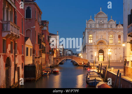 Vista sul Canal Rio dei Mendicanti illuminato con la Scuola Grande di San Marco, la facciata storica dell'Ospedale Ospedale e barche in blue n Foto Stock