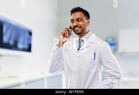 Dentista chiamando sullo smartphone in clinica dentale Foto Stock
