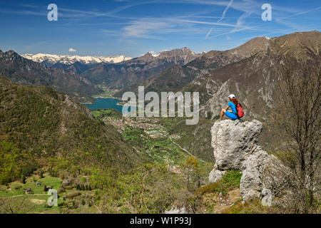 Donna seduta escursioni su roccia e guardando verso il lago di Tenno e gruppo Adamello, lago di Garda, montagne, Trentino, Italia Foto Stock