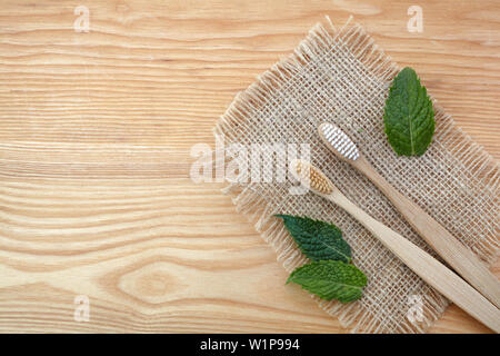 Rifiuti Zero concetto. Spazzolino da denti di bambù su sfondo di legno con verde foglia di menta. Libera in plastica essentials Foto Stock