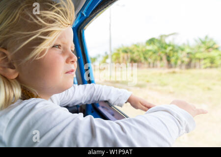 Ragazza guardando fuori della finestra, i capelli al vento, sulla strada da Cayo Coco a Santa Clara, sulla strada, vuoto street, senza traffico, a cavallo Foto Stock