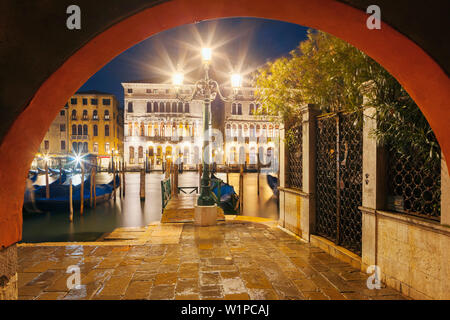 Affacciato sul Canal Grande con le facciate illuminate di palazzo Ca' Loredan e Palazzo Ca' Farsetti (da sinistra) in blu notte e gondole in Foto Stock