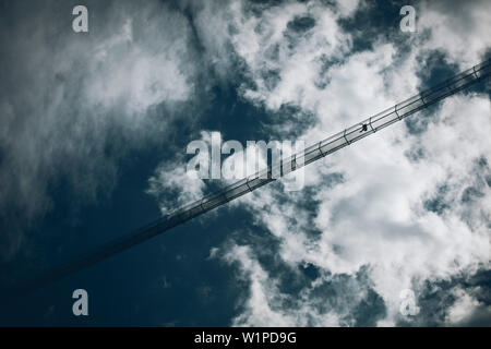 Escursionista sul ponte di sospensione a Holzgau, E5, Alpenüberquerung, seconda fase, Lechtal, Kemptner Hütte a Memminger Hütte, Tirolo, Austria, Alpi Foto Stock