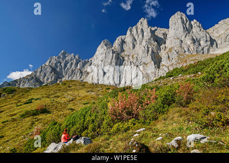 Donna seduta escursioni su roccia e guardando verso le pareti rocciose del Kaiser, Wilder Kaiser, Kaiser gamma, Tirolo, Austria Foto Stock