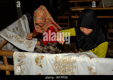 Yogyakarta, Indonesia - 2015.11.10: giovani donne applicando modelli in cera su tessuti in una fabbrica Batik Foto Stock