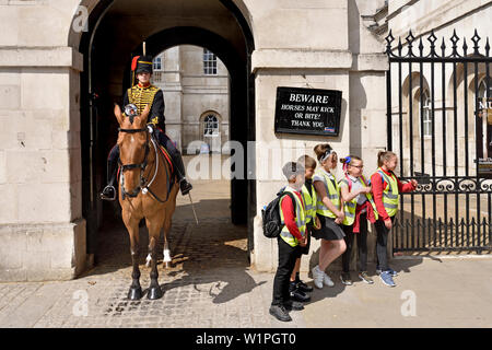 Londra, Inghilterra, Regno Unito. Elemento femmina del re di truppe, Royal cavallo artiglieria, in servizio al di fuori delle Guardie a Cavallo in Whitehall. Un gruppo di scolari posi Foto Stock