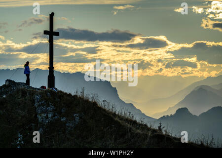 Woman Hiking permanente al vertice di Hochgern e guardando verso la vallata, Hochgern, Chiemgau Alpi, Alta Baviera, Baviera, Germania Foto Stock