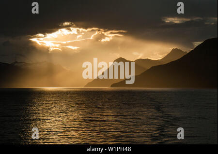 Sun irrompe attraverso il cloud-cover al largo della costa cilena, del Canale di Beagle, Alberto De Agostini National Park, Magallanes y de la Antartica Chilena, Patagonia Foto Stock