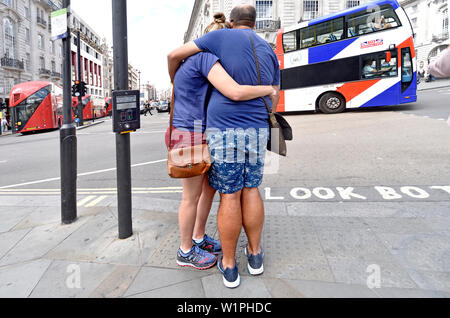 Londra, Inghilterra, Regno Unito. Giovane abbracciando in Piccadilly Circus - Union Jack bus turistici Foto Stock