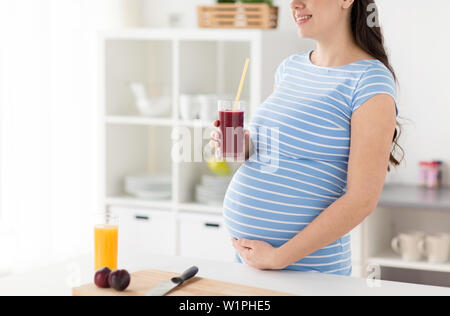 Donna incinta bere frullato di frutta a casa Foto Stock