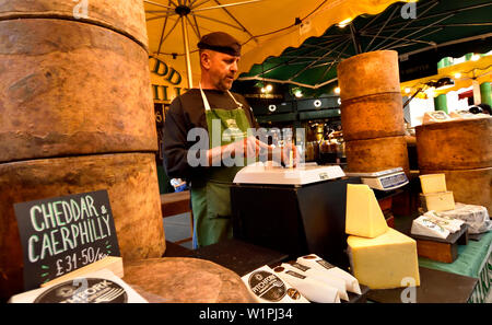 Londra, Inghilterra, Regno Unito. Borough Market, Southwark. Un uomo su un formaggio in stallo Foto Stock