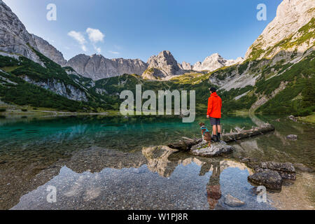 Escursionista con il cane presso il pittoresco lago Seebensee nel Mieminger montagne, Tirolo, Austria Foto Stock