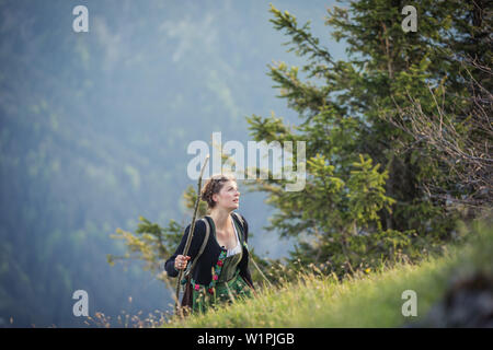 Giovane donna in costume tradizionale escursionismo sul Falkenstein nell'Allgaeu, Pfronten, Baviera, Germania Foto Stock