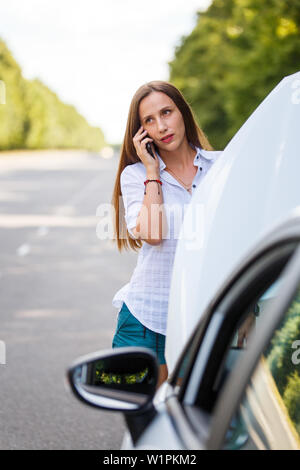 Giovane donna che chiama assistenza sui problemi con la sua auto. Foto Stock