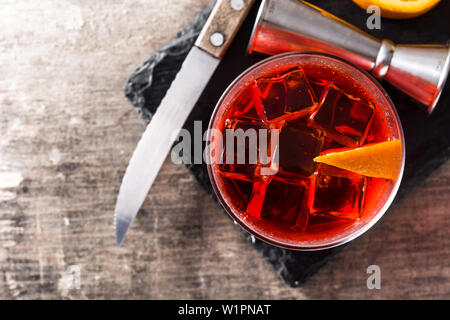 Negroni cocktail con un pezzo di Orange in vetro su un tavolo di legno. Vista dall'alto. Foto Stock
