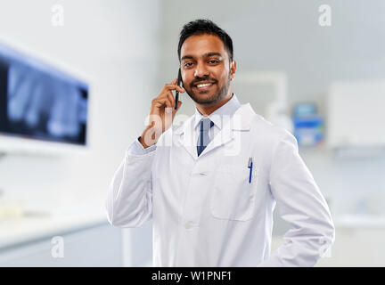 Dentista chiamando sullo smartphone in clinica dentale Foto Stock