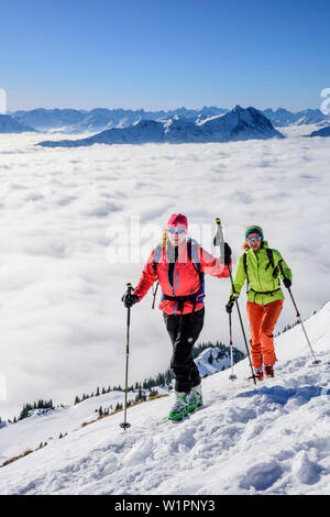 Due donne sci backcountry salendo verso Hinteres Sonnwendjoch, nebbia nella valle, Hinteres Sonnwendjoch, Alpi Bavaresi, Tirolo, Austria Foto Stock