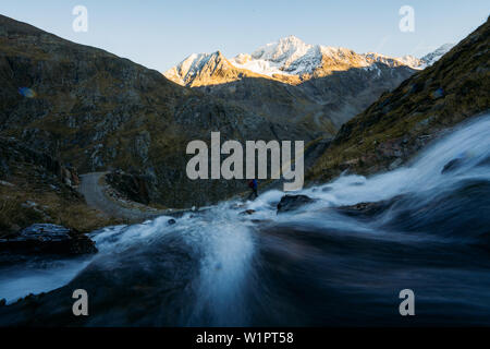 Cascata con un escursionista in background, E5, Alpenüberquerung, 6a tappa, sfiato,Niederjochbach, rifugio Similaun, Val Senales, serbatoio di Vernago, Merano Foto Stock