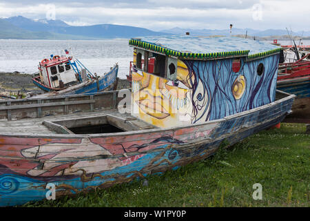 Dipinte in modo creativo spiaggiata barche giacciono sulla spiaggia vicino al porto di Puerto Williams, Magallanes y de la Antartica Chilena, Patagonia, Cile Foto Stock