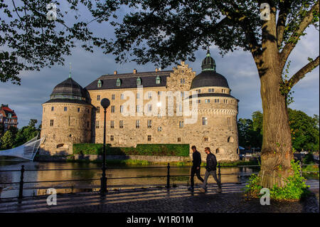 Giovani uomini andare per una passeggiata di fronte al castello di Oerebro, Svezia Foto Stock