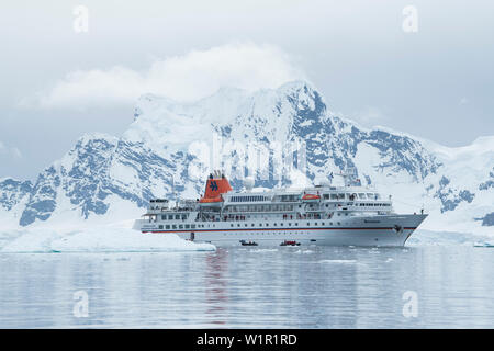 Expedition nave da crociera MS Bremen (Hapag-Lloyd Crociere), visto sotto una grande coperta di neve montagna, invia Gommone ZODIAC gommoni con passeggeri su un sc Foto Stock