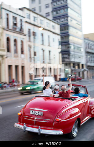 Red oldtimer, cabriolet, turisti, guidando lungo il Malecon, taxi, centro storico, centro città vecchia Habana Vieja, Centro Habana, famiglia viaggi a Cuba, h Foto Stock