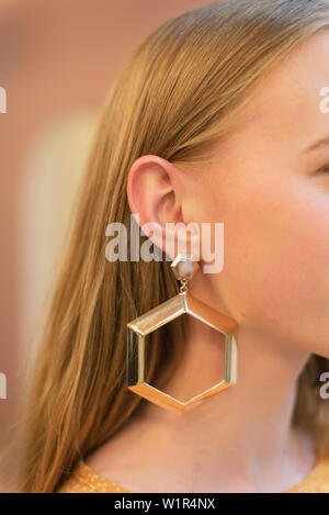 Grande, Golden, round orecchini su una ragazza bionda con i capelli dritti. Elegante e alla moda e orecchini di close-up. Foto Stock