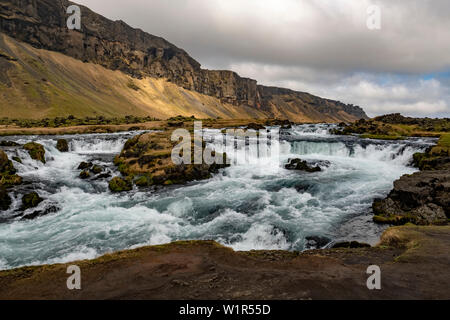 Infuriano river, cascate e aspro paesaggio sulla costa sud-orientale dell'Islanda nella tarda primavera. Foto Stock
