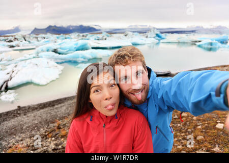 Funny selfie giovane tenendo self portrait fotografia su Islanda divertirsi sul viaggio Da Jokulsarlon laguna glaciale / lago glaciale. Il turista gode di splendida natura Islandese paesaggio Vatnajokull. Foto Stock