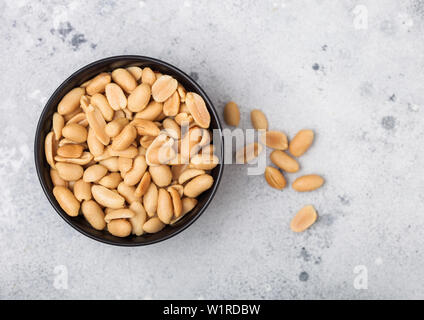 Salate e arachidi tostate classico snack in nero ciotola sul tavolo luminoso.vista superiore Foto Stock