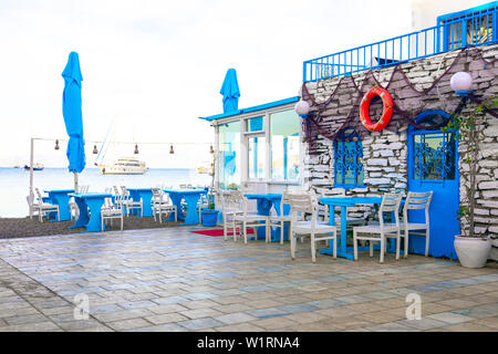 Vista del ristorante di pesce, cafe e fiori di bouganville sulla spiaggia in Gumusluk, Bodrum città della Turchia. Mare Egeo colorate in stile Sedie e tavoli. Foto Stock