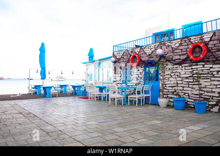 Vista del ristorante di pesce, cafe e fiori di bouganville sulla spiaggia in Gumusluk, Bodrum città della Turchia. Mare Egeo colorate in stile Sedie e tavoli. Foto Stock