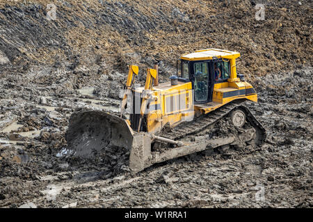 Giallo spinge apripista pile di grandi dimensioni di sporco su un sito in costruzione. Foto Stock