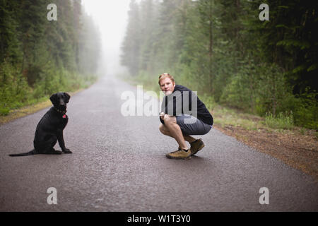 L'uomo con il suo cane su una strada Foto Stock