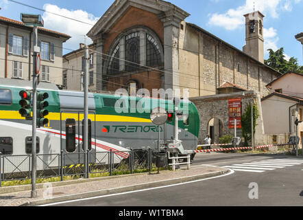 COMO, Italia - Giugno 2019: il moderno treno elettrico che passa su una strada che attraversa come esso si discosta dalla città di Como Il Lago di Como Foto Stock