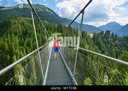 Donna camminando sul ponte di sospensione, Holzgau, Lechweg e la Valle del Lech, Tirolo, Austria Foto Stock