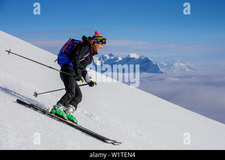 Donna sci backcountry discendente dalla Hinteres Sonnwendjoch, Kaiser gamma in background, Hinteres Sonnwendjoch, Alpi Bavaresi, Tirolo, Austria Foto Stock