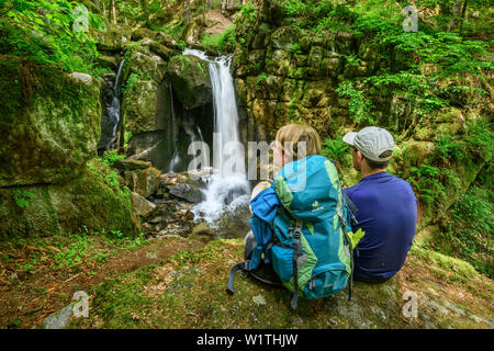 L uomo e la donna escursionismo guardando verso la cascata, cascata Hoellbach, Albsteig, Foresta Nera, Baden-Wuerttemberg, Germania Foto Stock