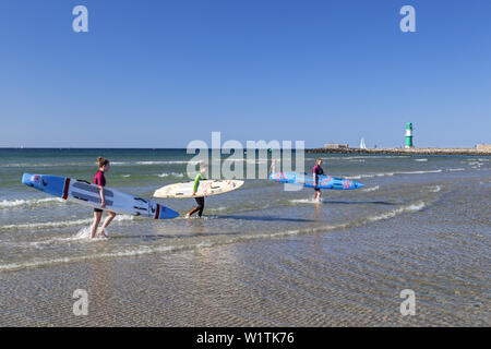 Bagnini sulla spiaggia, sullo sfondo il faro sul molo occidentale, Mar Baltico resort Warnemuende, città anseatica di Rostock, Mar Baltico Foto Stock