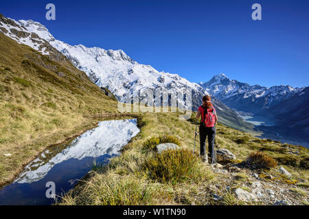 Woman Hiking accanto al lago di montagna con la riflessione, Mount Sefton, Mount Cook e Hooker valle in background, Hooker Valley, il Mount Cook National Par Foto Stock