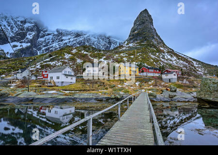 Ponte di legno che conducono verso la Norwegian case e montagne, il Cervino delle Lofoten, la Reine, Lofoten, Nordland, Norvegia Foto Stock