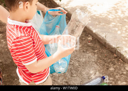 Madre e Figlio la raccolta di bottiglie di plastica. Famiglia eseguire Garbage Bag. Inquinamento di plastica sulla terra. Spazio di copia Foto Stock