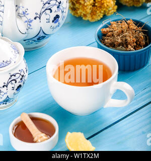 Tazza di tè di tiglio, essiccati i fiori di tiglio in tazza con miele e limone su sfondo di legno. Foto Stock